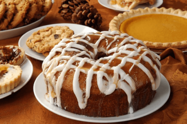 A golden-brown Bundt cake with a dusting of powdered sugar on a white serving platter